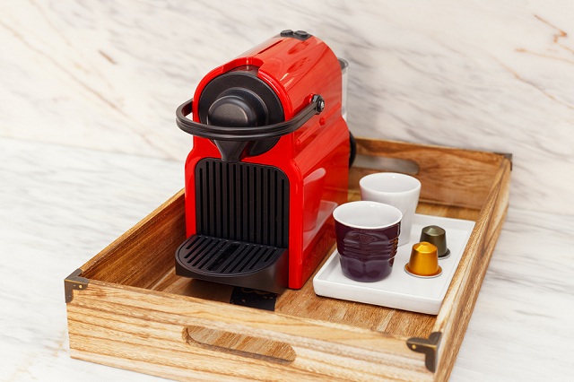 Best nespresso machine reviews by Fourth Estate Coffee. Image is a single nespresso machine on a wood tray with two cups on the side.